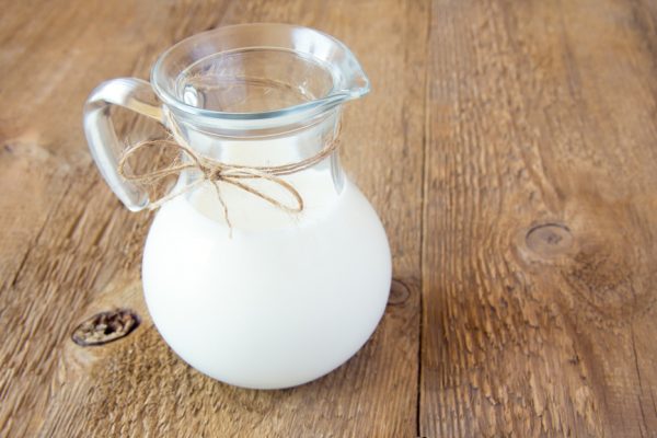 Молоко в прозрачном кувшине на деревянном столе