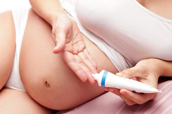 Беременная женщина выдавливает средство из тюбика