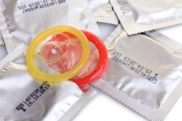 Красный, жёлтый презервативы лежат на запакованных